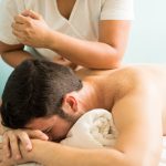 Profile view of a young man getting a lomi lomi massage in a spa clinic